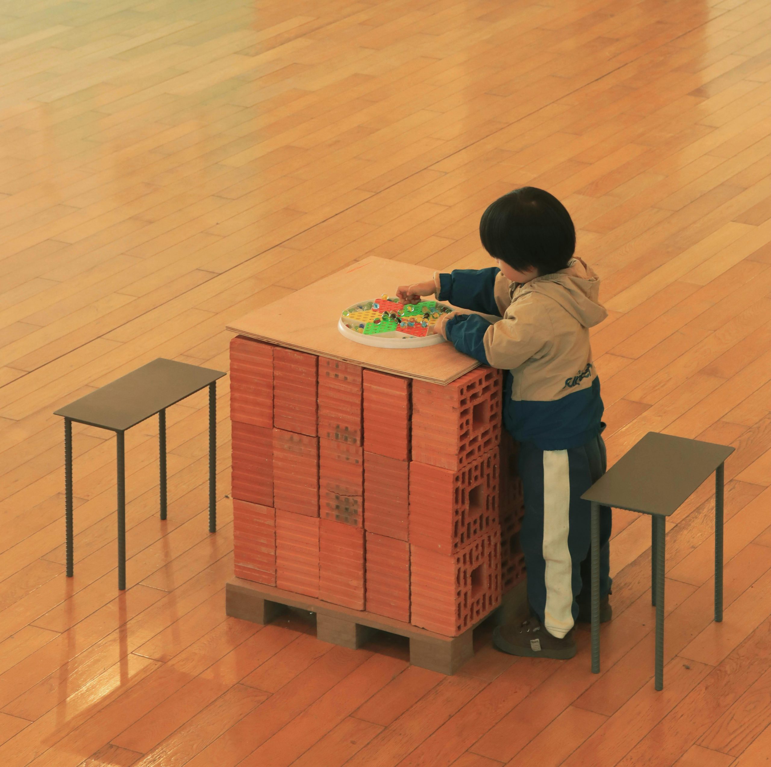 Young child playing with a toy on a brick palette indoors, creating a scene of creativity and imagination.
